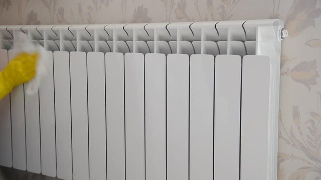 Female hand in  rubber glove cleans heating radiator