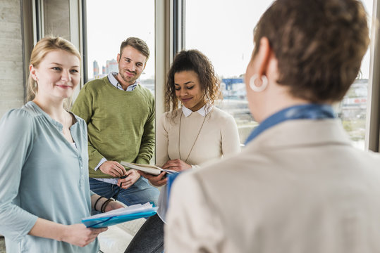 Three smiling colleagues in office looking at mature woman