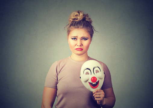 upset woman with sad expression holding clown mask expressing happiness