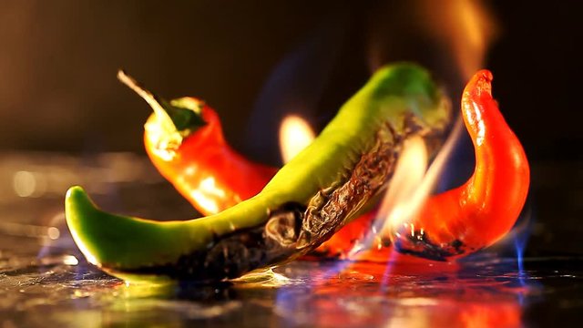hot pepper in fire arms   /   hot pepper in flames on a black background