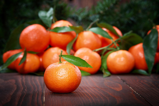 Tangerines with leaves on wooden surface