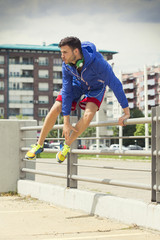 Handsome young athlete jumping over the fence