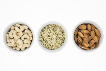Cashews, hemp meal and unblanched almonds in bowls, on white background