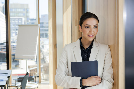 Gesch&auml;ftsfrau,Mappe,Flipchart,denken,l&auml;cheln,Zufriedenheit,stehen