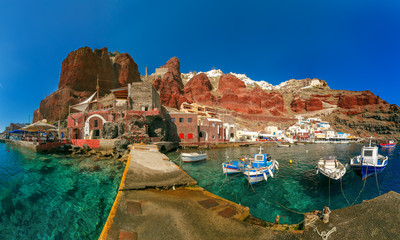 Panoramic view with fishing boats at Old port Amoudi of Oia village at Santorini island in Aegean...