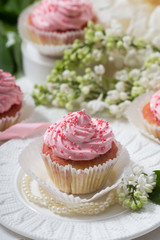Vanilla cupcakes with pink cream on a white table,white flower and leaf, lilac, selective focus, close up