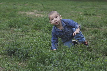 Small child is risign with one hand from the grass