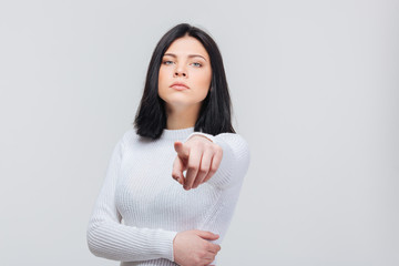 Serious brunette girl pointing at you