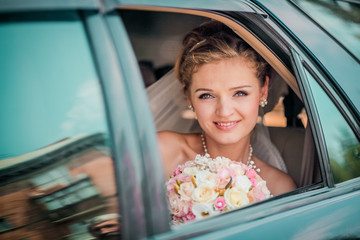 Beautiful Bride in Car on wedding day looking out Window. Bride smile emotions