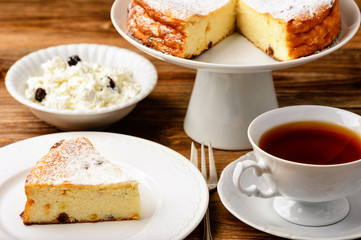 Cheesecake slice and cup of tea on wooden background.