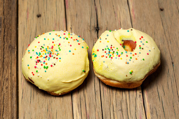 two donut with colorful decor. Isolated on wooden background