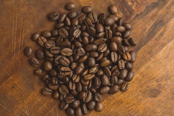 Brown coffee beans in circle shape, closeup of macro coffee beans for background and texture. On brown wooden board.