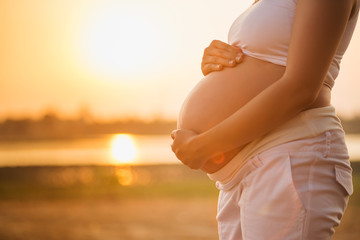 Pregnant woman relaxing lakeside sunset background
