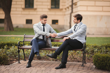 Two stylish businessmen shaking hands in suits