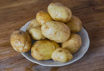 Potatoes skin washed uncooked on polka dot plate wooden table vintage