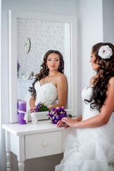 Happy and beautiful bride looks in the mirror