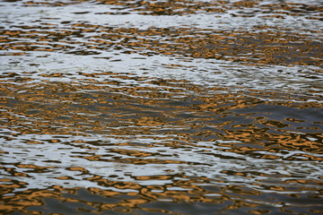 Orange blue white reflection on surface water with waves