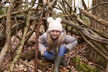 Naklejka na ściany i meble Young girl sits under shelter of tree branches, full length