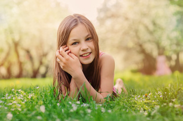 summer outdoor close up portrait of beautiful happy kid girl lying on the grass in park