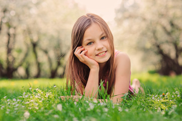Naklejka na ściany i meble summer outdoor close up portrait of beautiful happy kid girl lying on the grass in park