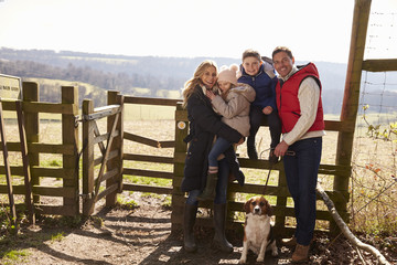 Happy family with dog by a gate in the countryside