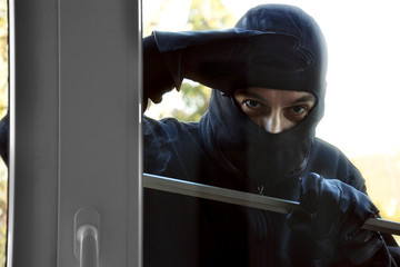Einbrecher vor Raub und Diebstahl schaut durch Fenster in Haus oder Wohnung