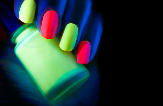 Fluorescent nail polish. Fashion model woman nails in neon light