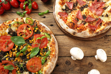 due pizze con prosciutto mozzarella pomodori su sfondo di legno rustico