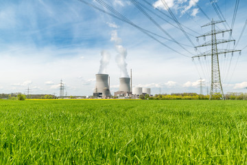 Nuclear power plant with green field and big blue clouds