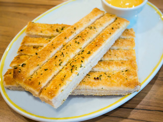Fresh breadsticks served with dip sauce on white plate