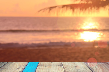 Obraz na płótnie Canvas Blur tropical sunset beach with bokeh wave on old empty wood table