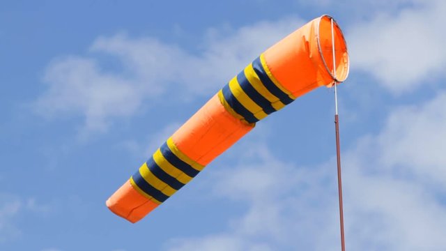 Orange color windsock in airport on the blue sky