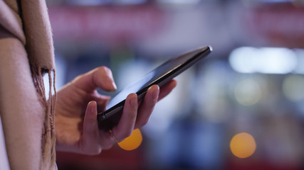 Hands of a  female using a cell phone at night in the city