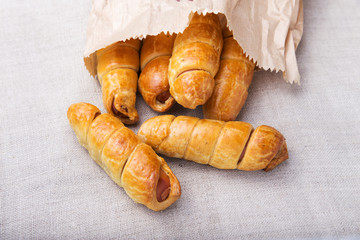 Sausage in the dough in a paper bag on a linen napkin, fast food