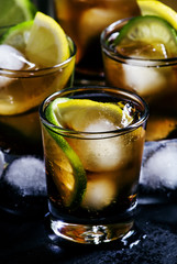 Fizzy alcoholic drink with cola, lemon, lime and ice cubes, blac