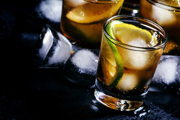 Fizzy alcoholic drink with cola, lemon, lime and ice cubes, blac