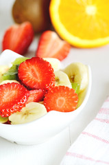 Bowl with fruit salad - pieces of strawberry, orange and kiwi