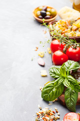 Fototapeta na wymiar Italian food background with vine tomatoes, basil, spaghetti, olives, parmesan, olive oil, garlic