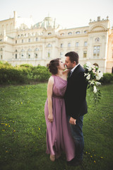 Wedding. Couple. Krakow. The bride in a pink dress and groom posing on background of theater