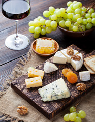 Red wine in glass with cheese, honey, nuts and grape.