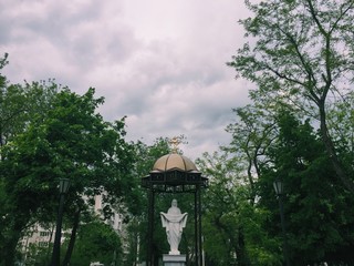 белая гранитная статуя Девы Марии под куполом под небом возле церкви