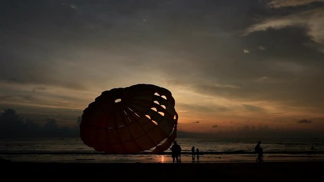 Silhouette of man is preparing para sailing at the sunset beach