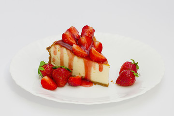 Slice cheesecake with fresh strawberries on white plate