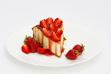 Slice cheesecake with fresh strawberries on white plate