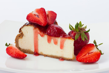 Slice cheesecake with fresh strawberries on white plate
