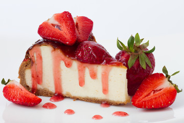 Slice cheesecake with fresh strawberries on white plate