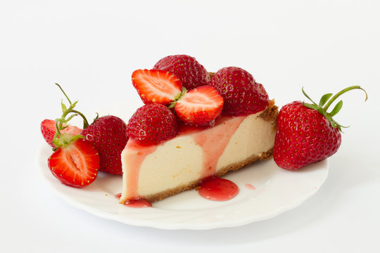 Slice cheesecake with fresh strawberries on white plate
