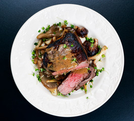 Tasty Beef Mignon steak with mushrooms and herbs on plate.