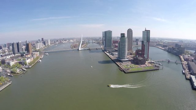 Aerial of Rotterdam city flying towards Erasmus Bridge Erasmusbrug showing business dsitrict right boat sailing past cityscape bird view of city center large city in south of Netherlands Holland 4k