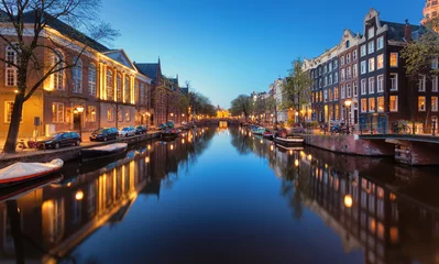 Papier Peint photo Canal Beau paysage urbain de nuit à Amsterdam, Pays-Bas. Lumières de la ville reflétées dans l& 39 eau avec un ciel bleu. Éclairage nocturne des bâtiments et des bateaux près de l& 39 eau du canal. Magnifique vue sur les maisons
